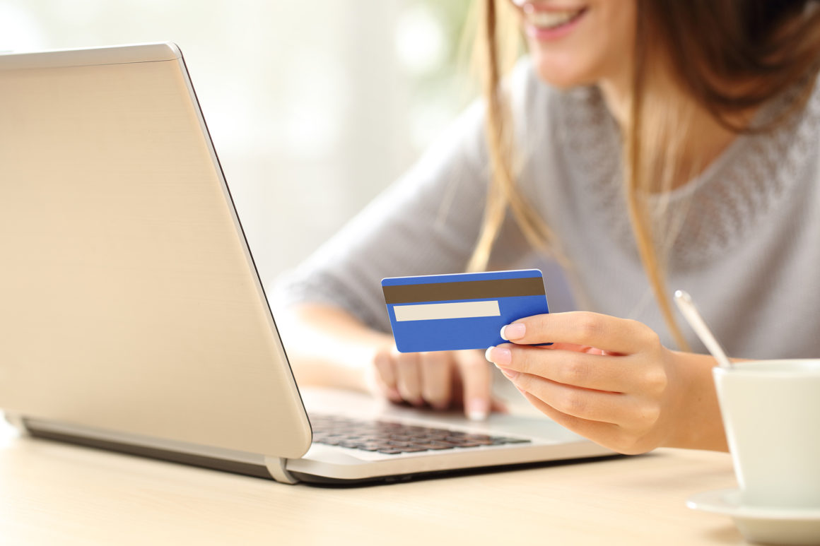 happy young woman paying her apartment rent online with a laptop