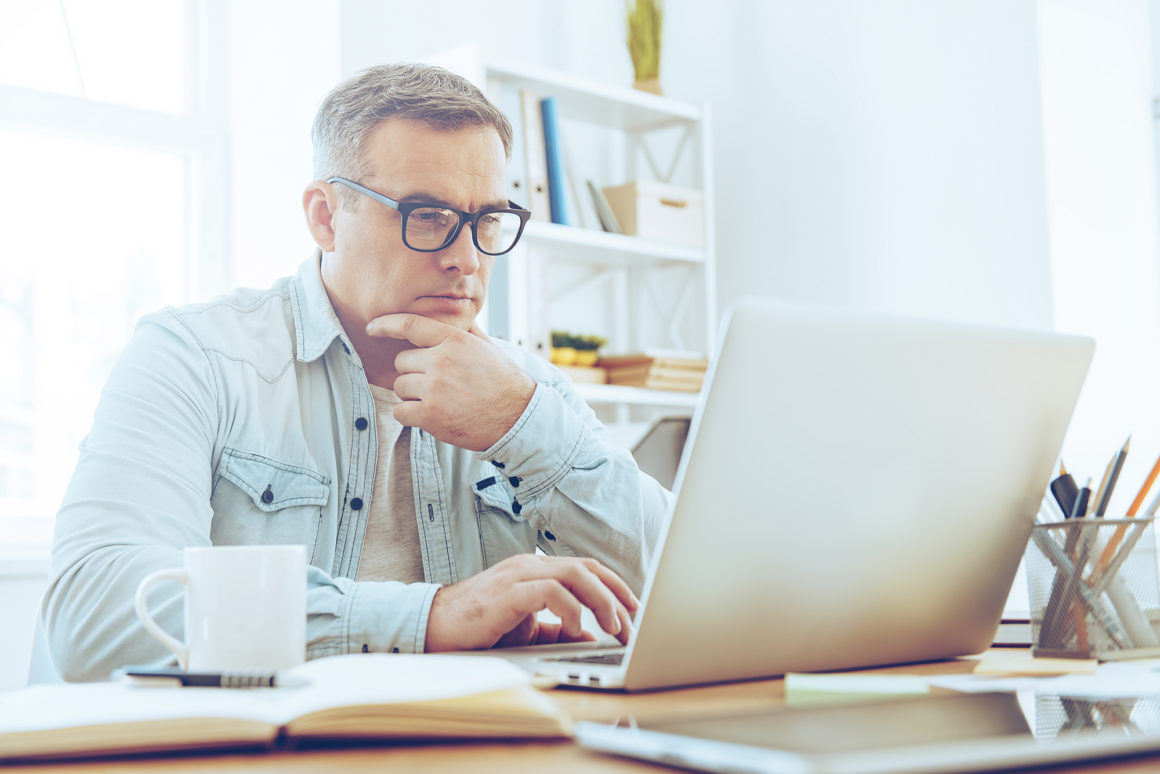 elderly man drinking coffee paying his apartment bill online