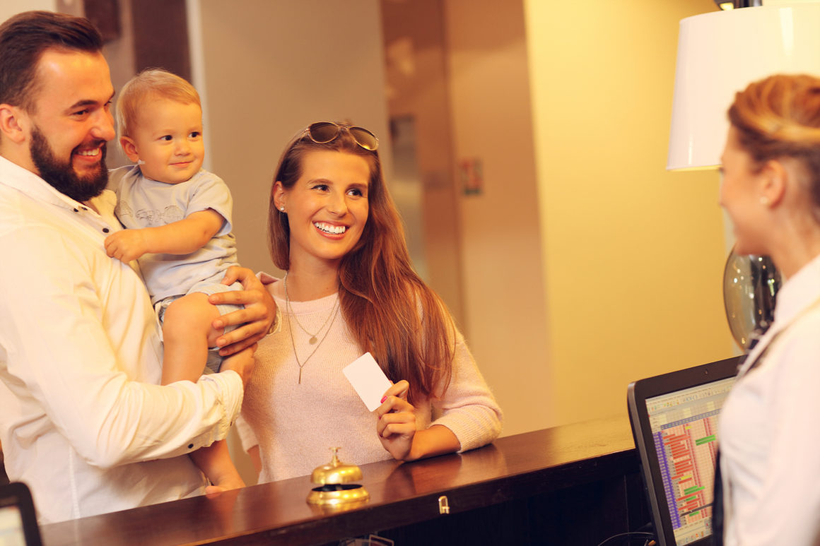 happy young family being helped by concierge staff at the front desk