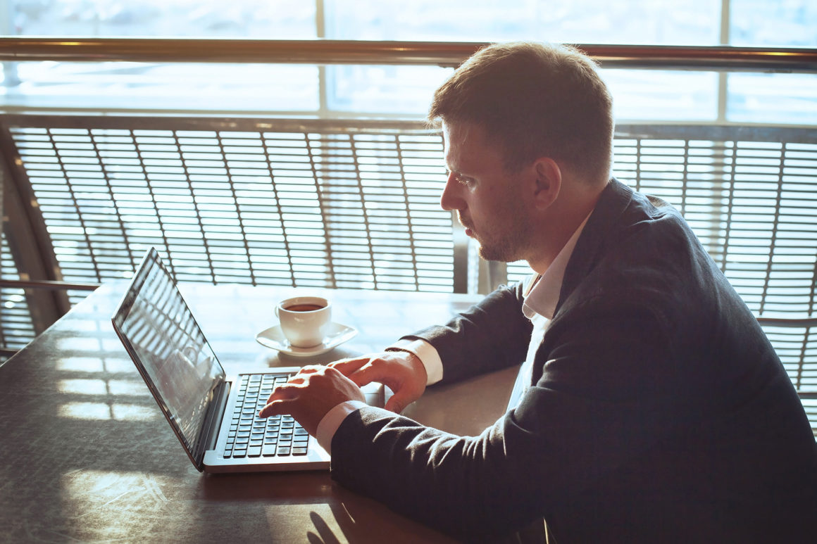 business man in a suit drinking coffee while paying his apartment rent online