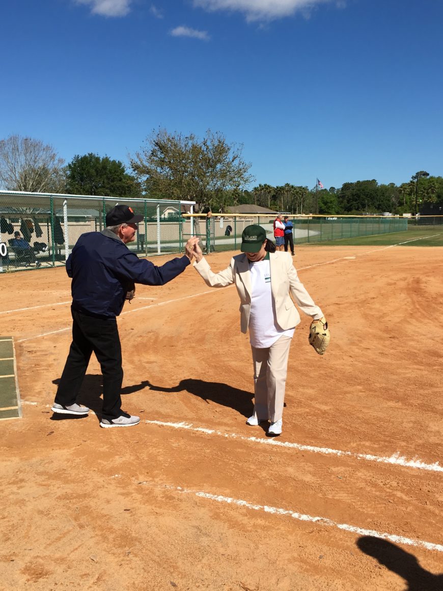 two players high-fiving on a baseball field during the leland games