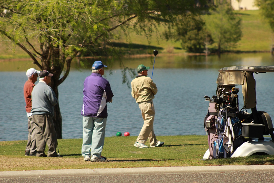 one man playing golf with three men watching at leland games